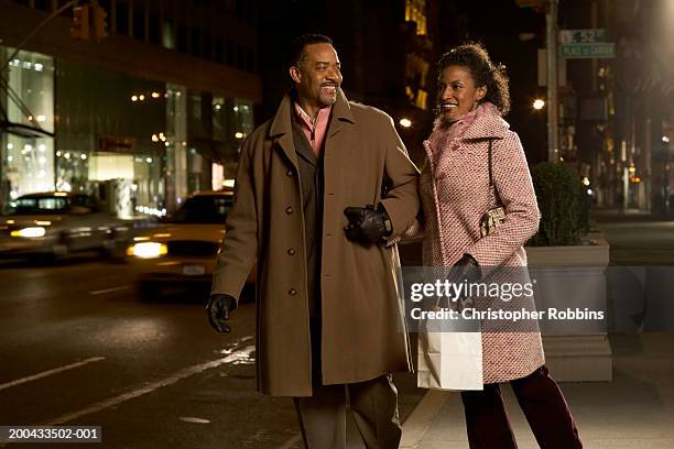 mature couple standing on pavement holding hands, smiling, night - brown coat bildbanksfoton och bilder