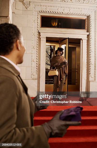 mature woman entering hotel foyer, smiling, man in foreground - well dressed couple stock pictures, royalty-free photos & images