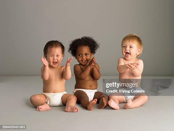 baby girl (14-16 months) sitting between two baby boys (10-14 months) - diapers stock pictures, royalty-free photos & images