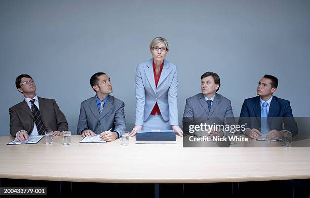 businesswoman flanked by businessmen standing up from boardroom table - female with group of males stock pictures, royalty-free photos & images