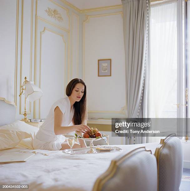 young woman eating fruit on bed - paris nice 個照片及圖片檔