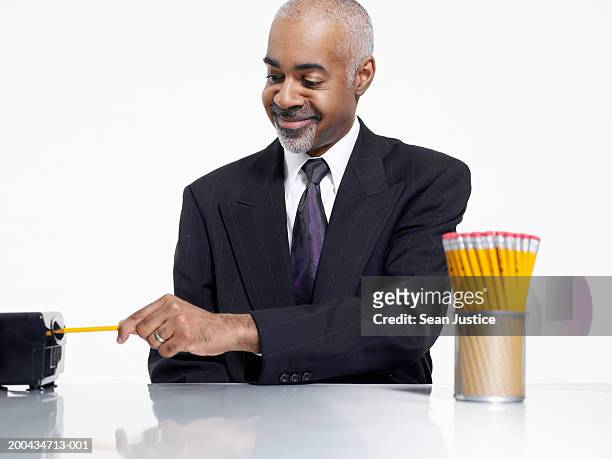 mature businessman sharpening pencils, close-up - sharpening stock-fotos und bilder