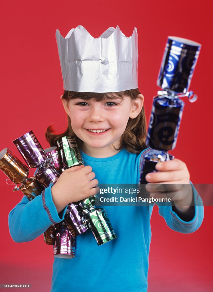 Girl (3-5) holding Christmas crackers, smiling, portrait