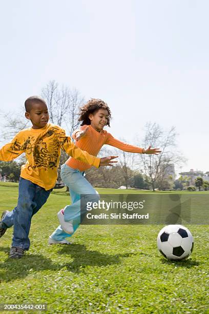 children (7-10) playing soccer in park - ir atrás de imagens e fotografias de stock