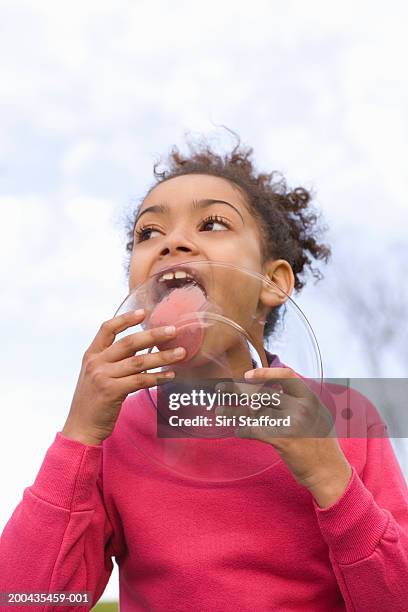 girl (8-10) licking plastic plate, low angle view - girls licking girls stockfoto's en -beelden