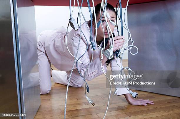 young woman crawling under desk sorting through electric cables - businesswoman under stock pictures, royalty-free photos & images