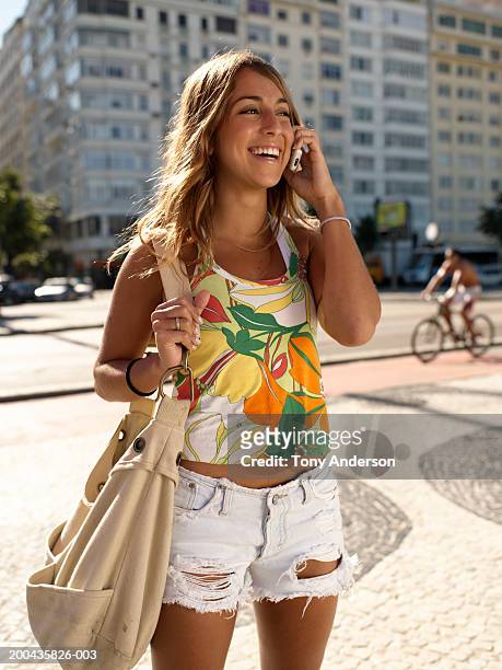 young woman using mobile phone with handbag, smiling - girl in tank top stock pictures, royalty-free photos & images