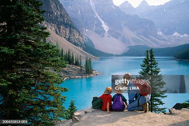 canada, alberta, mother and children looking at lake moraine, rear view - moraine lake stock-fotos und bilder