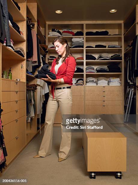 woman holding folded  sweaters in walk-in closet - placard fotografías e imágenes de stock
