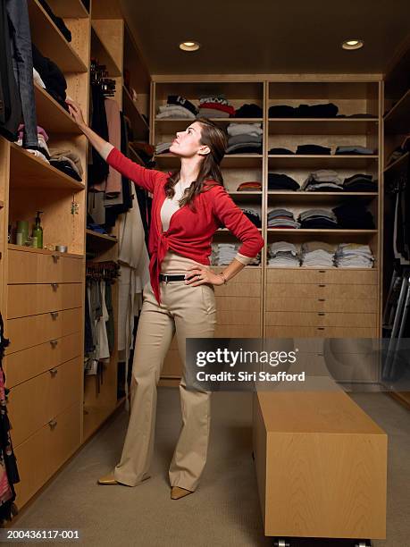 woman looking at folded clothing on shelves in walk-in closet - armadio a muro foto e immagini stock