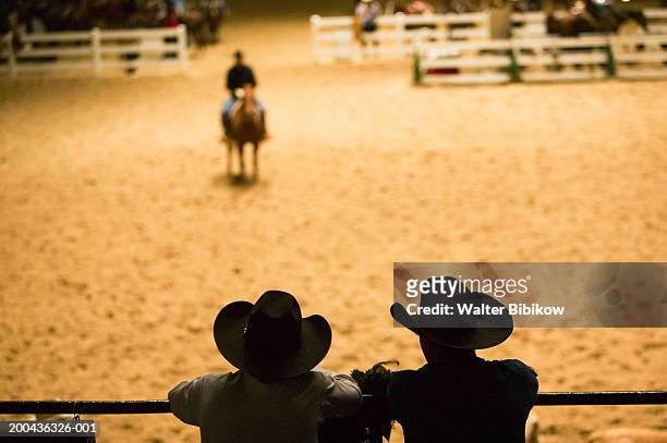 silhouette of cowboys at indoor rodeo - rodeo stock-fotos und bilder