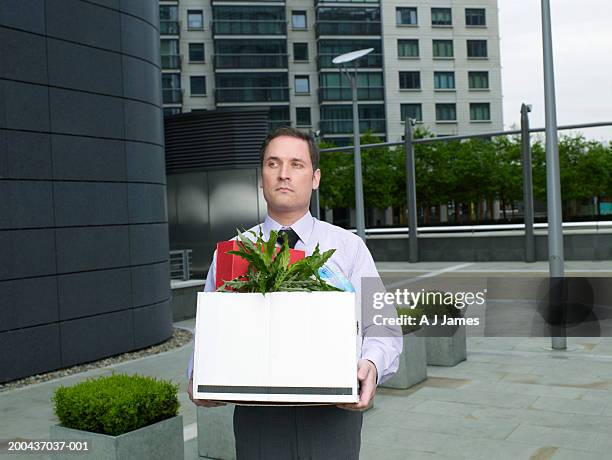 businessman carrying box containing plant and files on street - guy in white shirt stock pictures, royalty-free photos & images