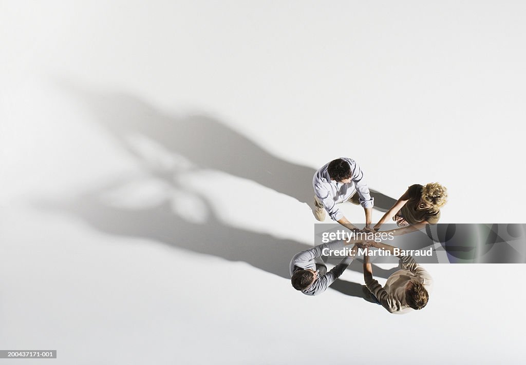 Four people placing hands over each other's, overhead view