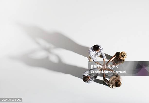 four people placing hands over each other's, overhead view - four people foto e immagini stock