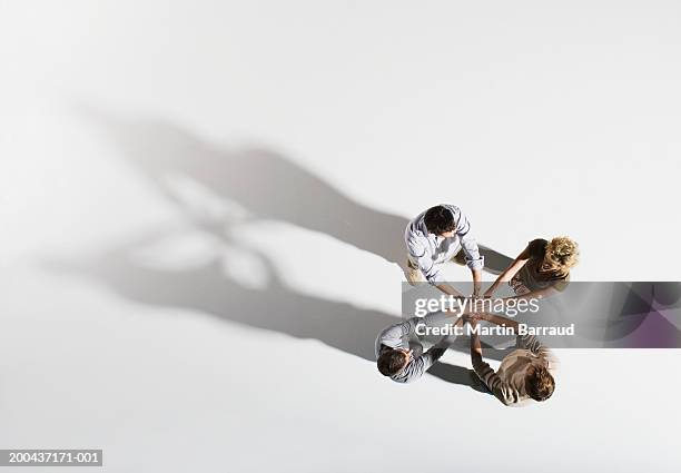 four people placing hands over each other's, overhead view - quatro pessoas imagens e fotografias de stock