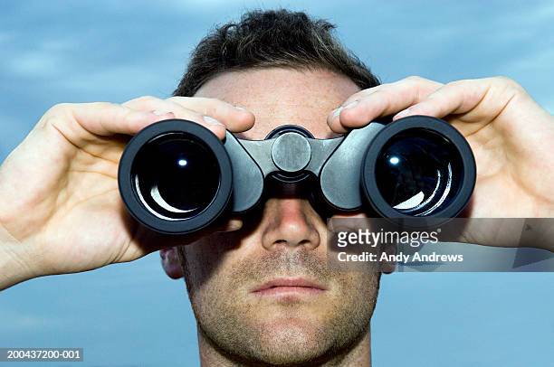 man looking through binoculars outdoors, close-up - viewing binoculars stock pictures, royalty-free photos & images