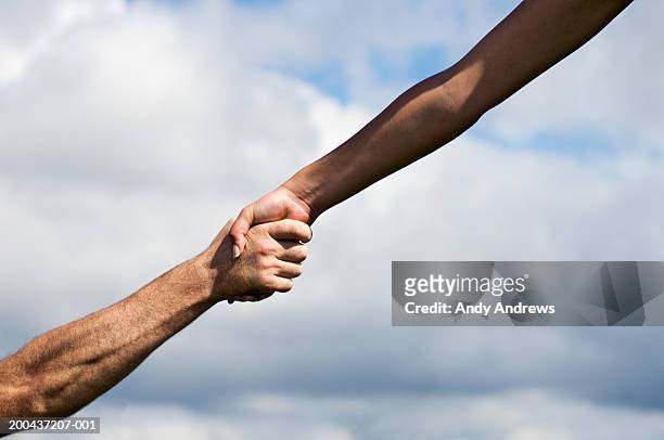 man and woman outdoors clasping hands, close-up - clasped hands stock-fotos und bilder