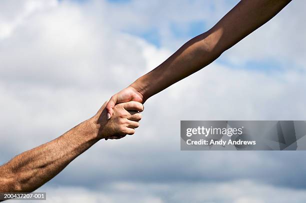 man and woman outdoors clasping hands, close-up - helping hand fotografías e imágenes de stock