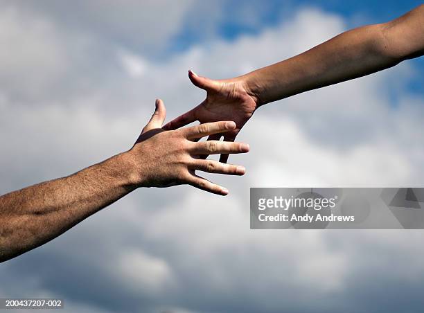 man and woman outdoors reaching out hands, close-up - a helping hand stock pictures, royalty-free photos & images