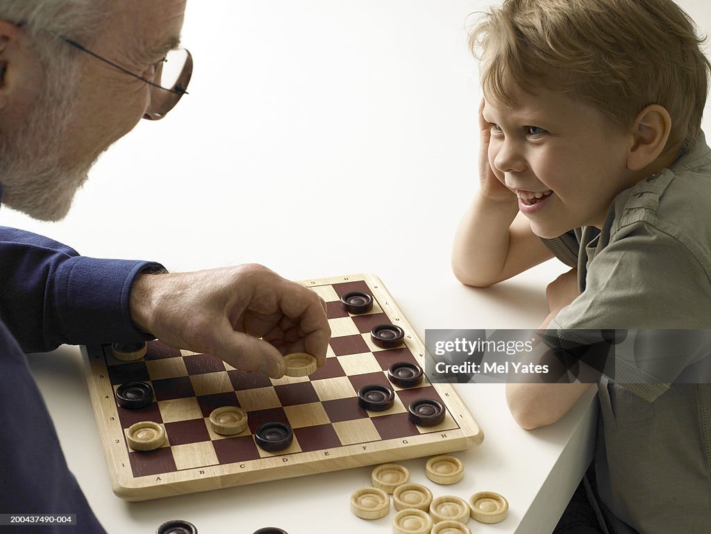 Boy (5-7) playing draughts with grandfather, close-up