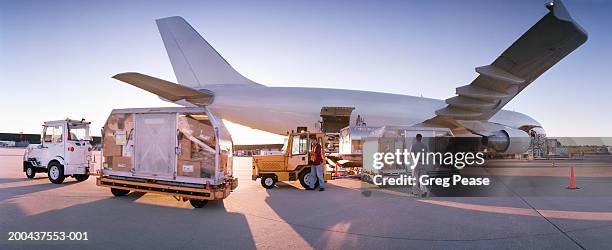 men unloading cargo plane, sunset - frachtflugzeug stock-fotos und bilder