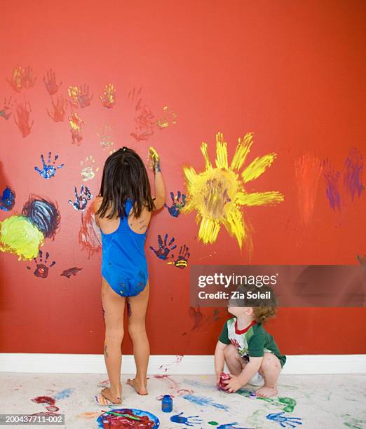 male toddler (12-15 months) wathing girl 4-6) fingerpainting - baby paint stock pictures, royalty-free photos & images