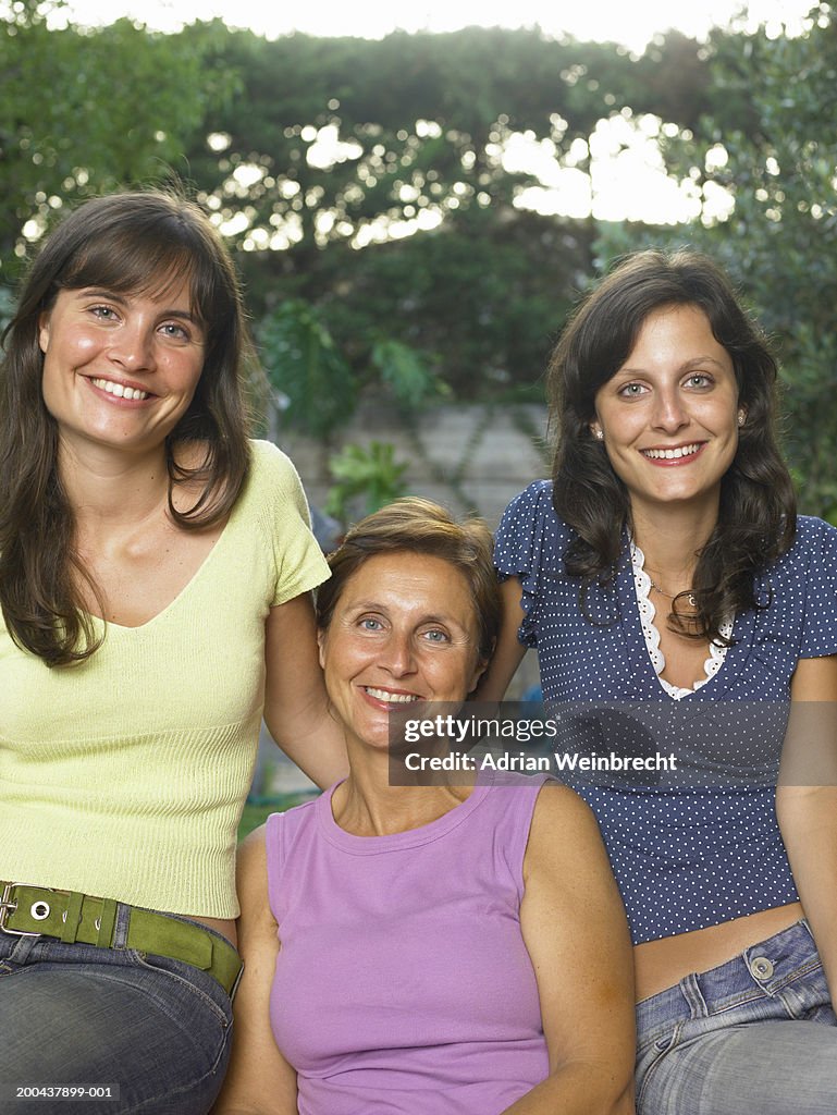 Mature woman with two adult daughters, outdoors, smiling, portrait