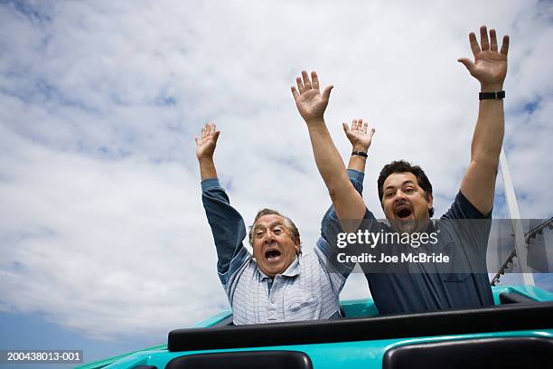 father and adult son riding rollercoaster, hands in air - rollercoaster stock pictures, royalty-free photos & images