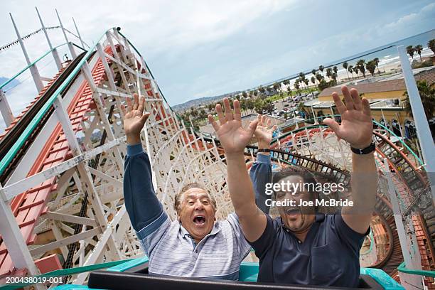 father and adult son riding rollercoaster, hands in air - dad son fun stock pictures, royalty-free photos & images