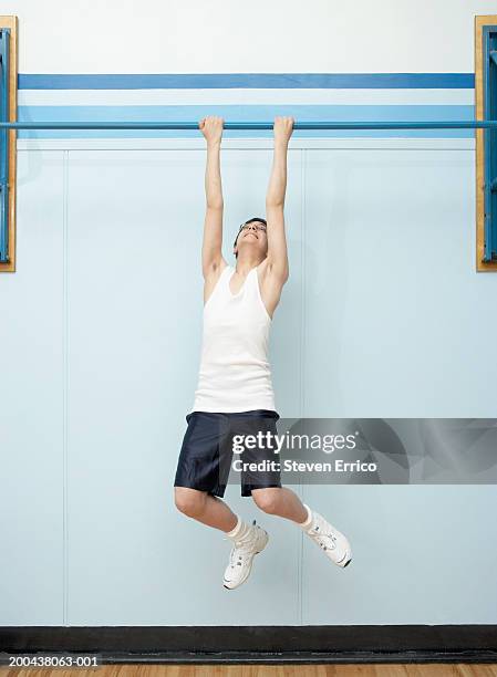 boy (11-13) doing chin-ups in school gymnasium - boys in pullups stockfoto's en -beelden