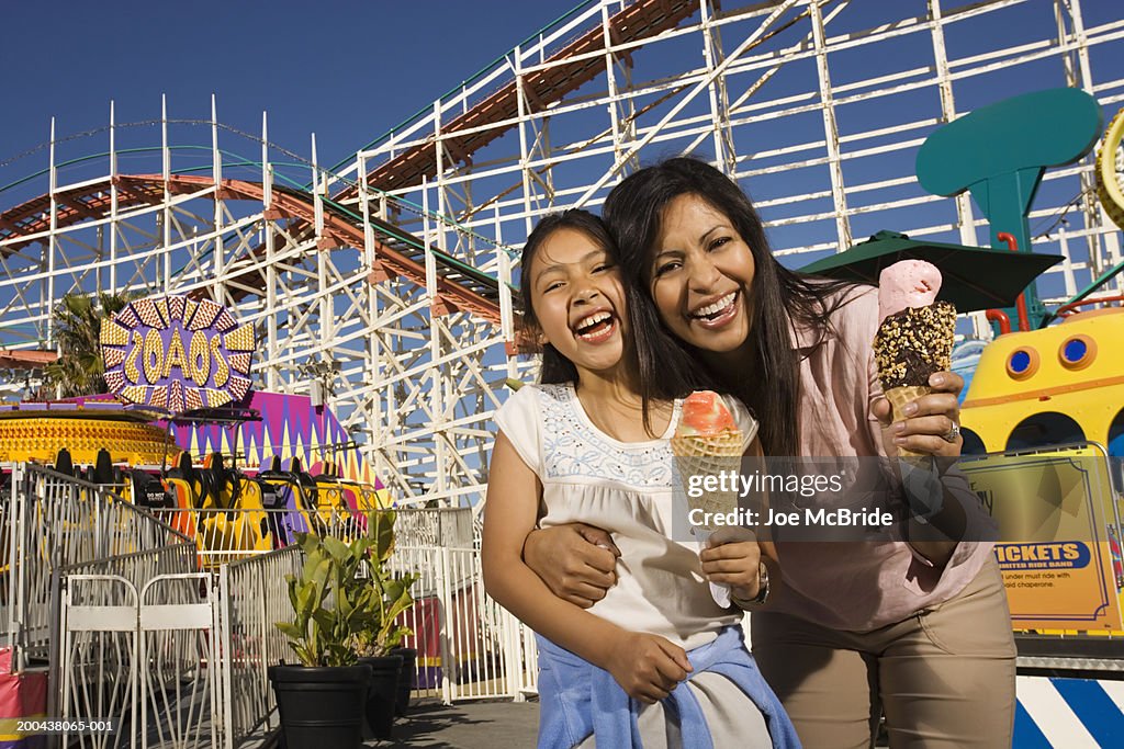 Mother and daughter (8-10)holding ice cream cones at amusement park