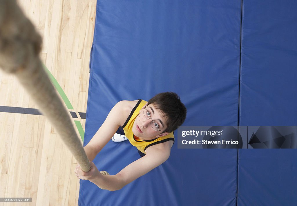 Boy (11-13) preparing to climb rope in school gymnasium, elevated view