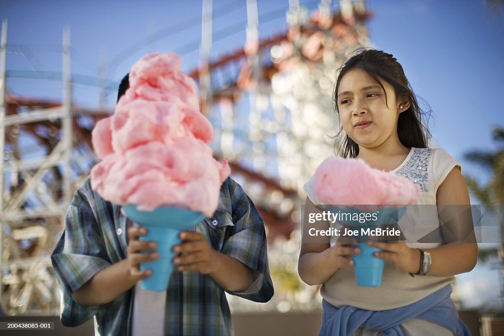 Children (9-11) holding cotton candy at amusement park