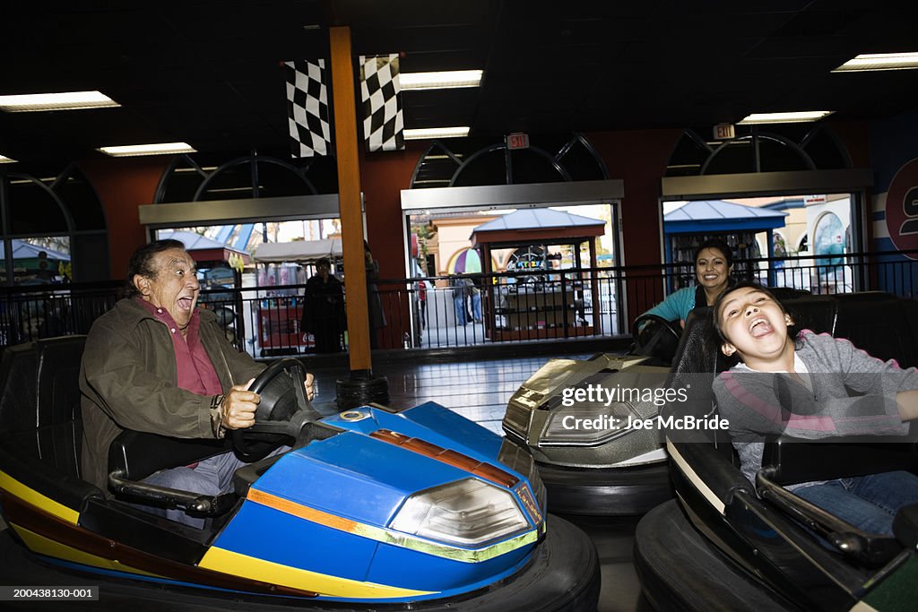 Three generation family riding bumper car at amusement park