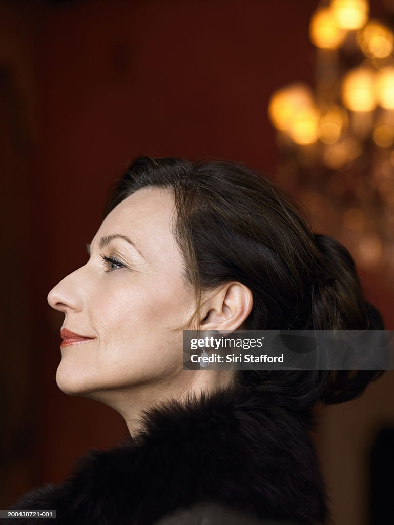 Mature woman wearing black top with fur, profile