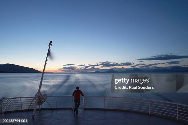 usa, alaska, man standing on back of state ferry, sunset, rear view - fähre stock-fotos und bilder