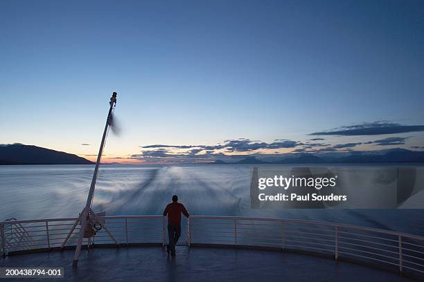 usa, alaska, man standing on back of state ferry, sunset, rear view - popa fotografías e imágenes de stock