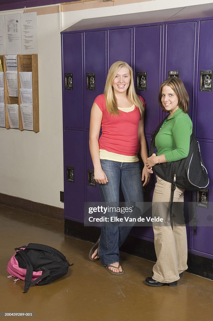 Two teenage girls (16-18) beside lockers in school corridor, portrait