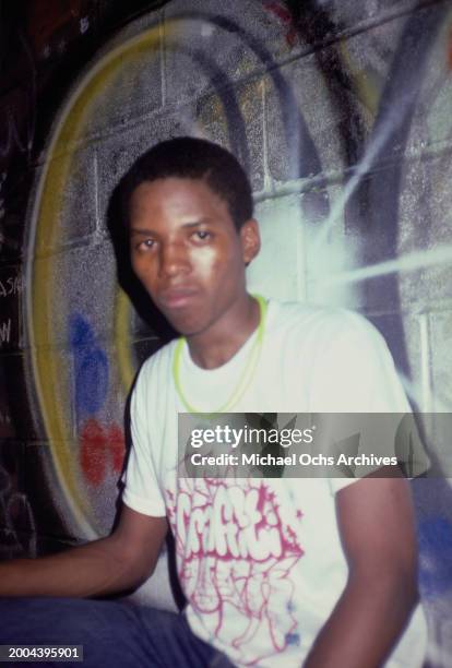 Man model, wearing a t-shirt with a graffiti motif on the chest, a graffiti-strewn wall behind him, attends the Graffiti Fashion Show, held at the...