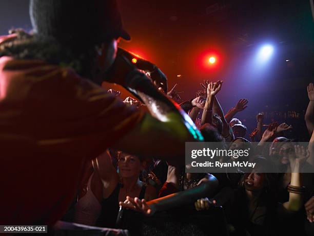 man singing on stage in nightclub, crowd cheering, arms raised - ryan singer stockfoto's en -beelden