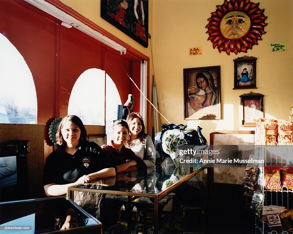 Young women standing behind counter in shop, portrait