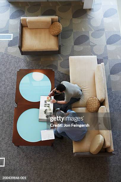 two businessmen looking at design book, elevated view - coffee table books stockfoto's en -beelden