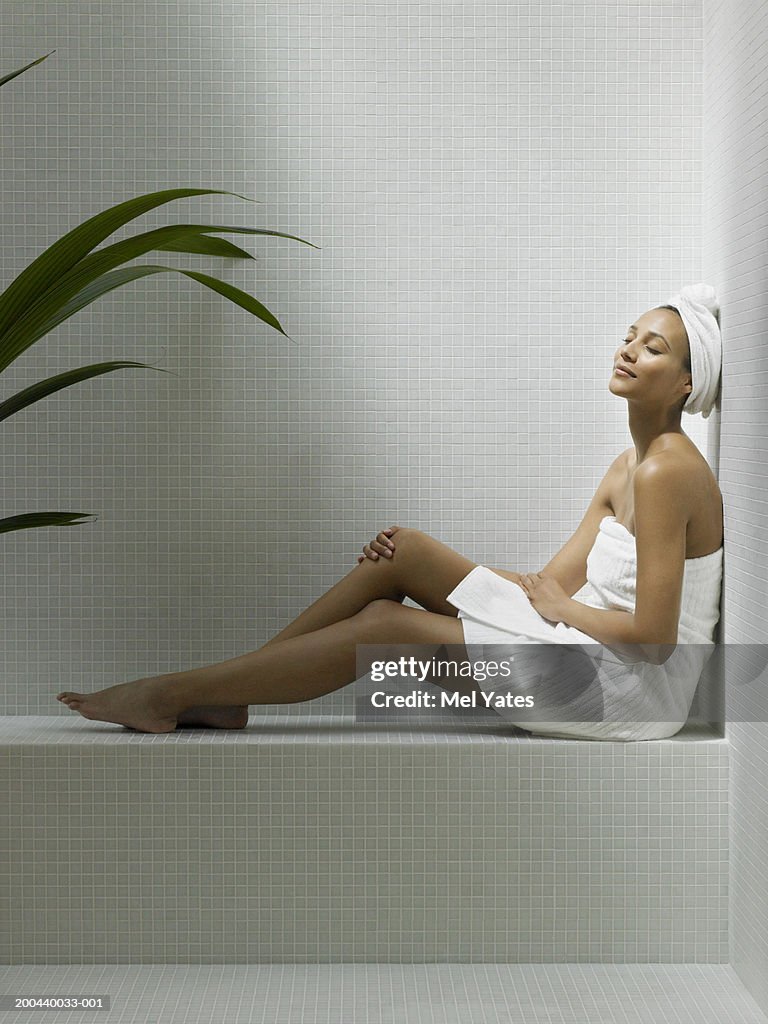 Young woman relaxing in sauna, eyes closed