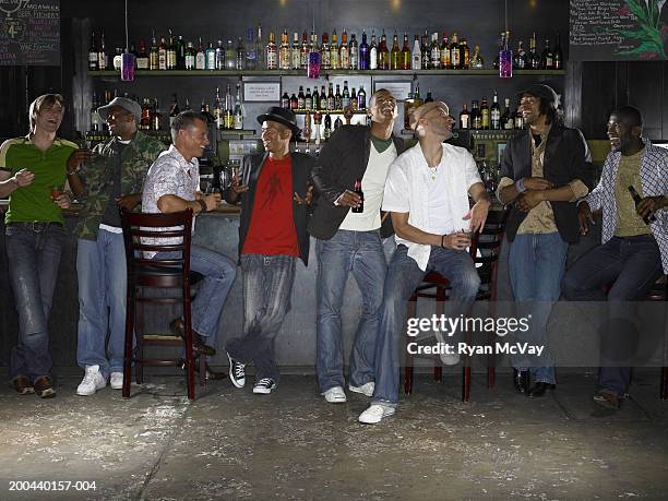 eight men drinking alcohol and laughing in bar - bar man t shirt stock-fotos und bilder