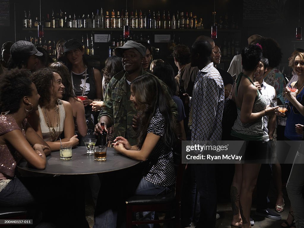 Adults talking and drinking cocktails in nightclub