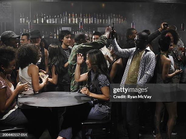 group of adults drinking cocktails and talking in nightclub - beer bar photos et images de collection