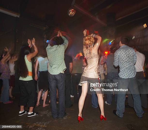 group of adults dancing in nightclub, arms raised, rear view - disco shoe stock pictures, royalty-free photos & images