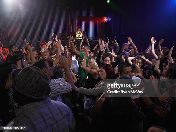 crowd dancing and clapping in nightclub, dj in background - night club foto e immagini stock