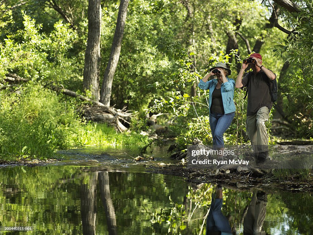 Mature couple with binoculars in woods