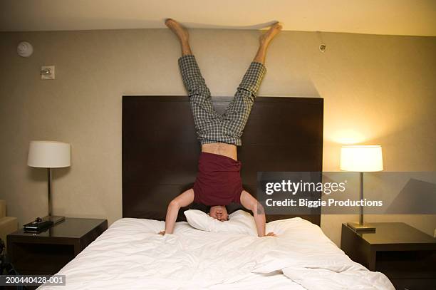 man standing on head on bed - akrobatische aktivität stock-fotos und bilder